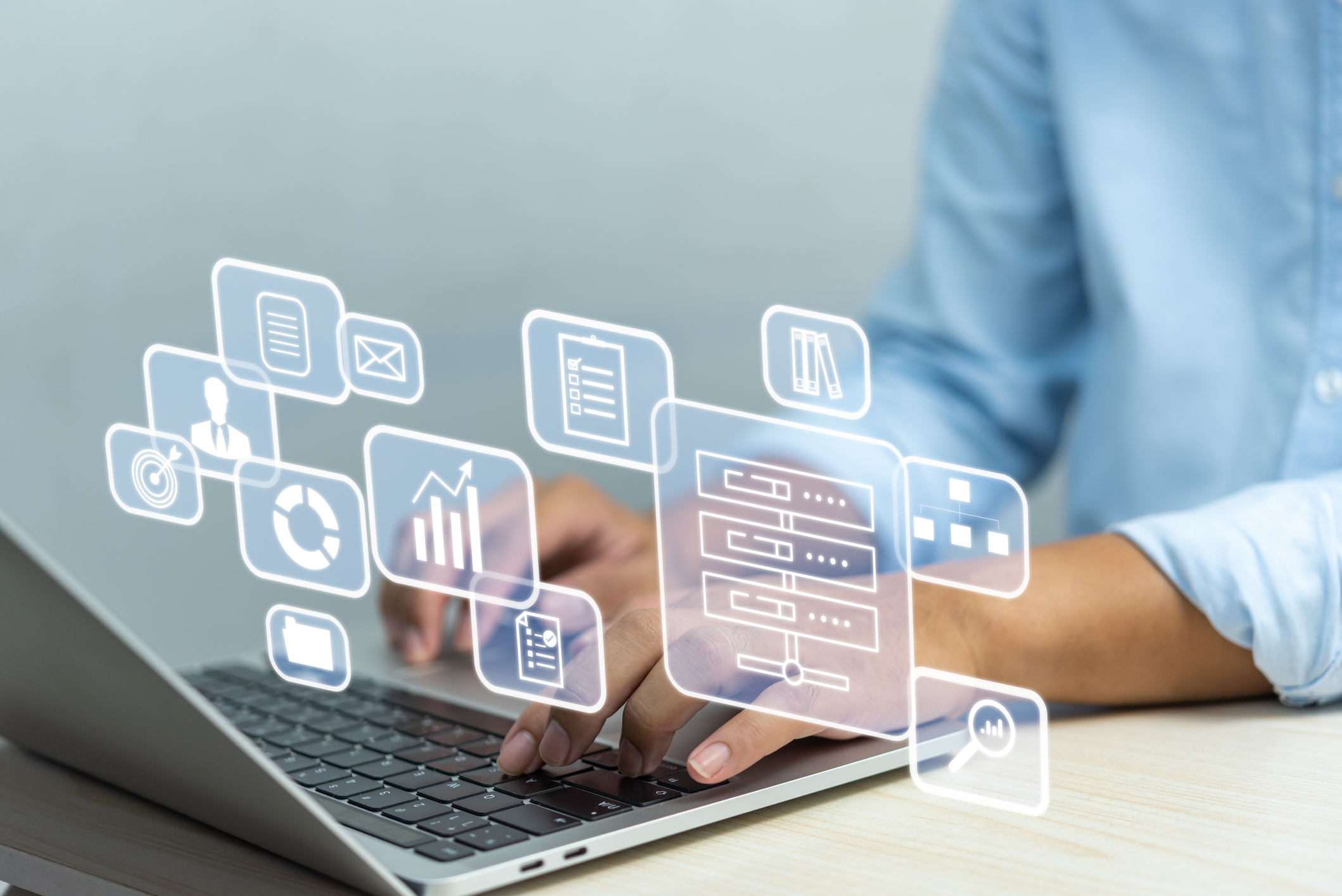Digital transformation concept — worker at desk with notebook computer, iconography in the foreground.