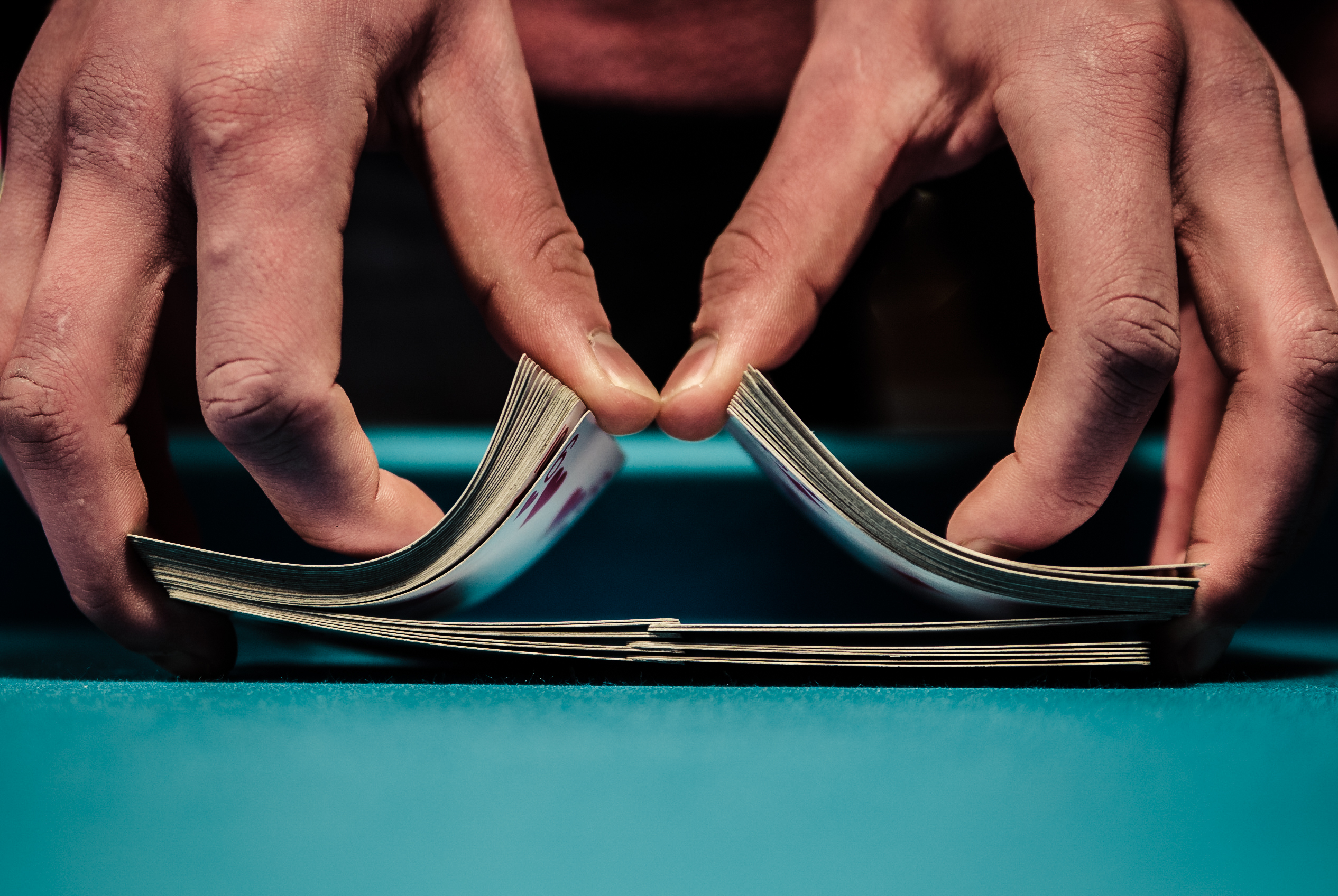 Two hands shuffling cards on a blue table