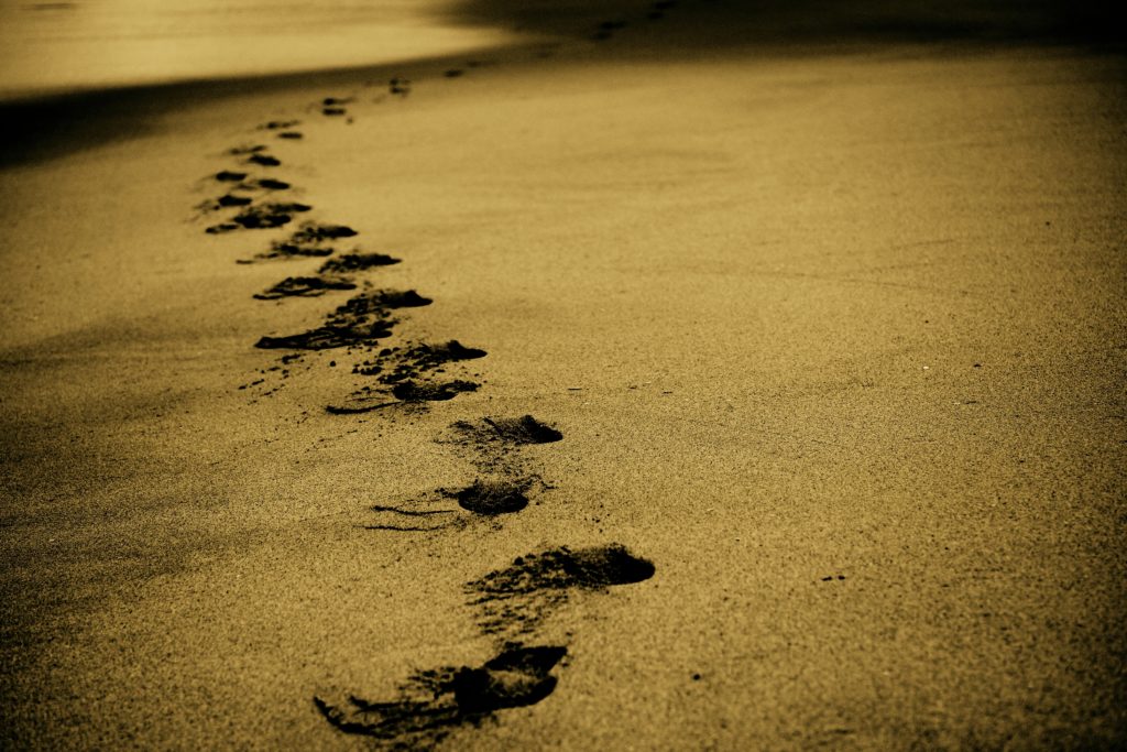 Footsteps along a beach, signifying a journey of many steps.