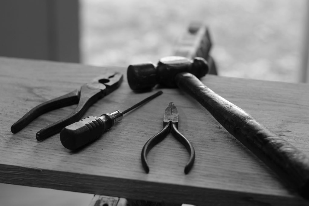 Four assorted tools laid out on a bench.