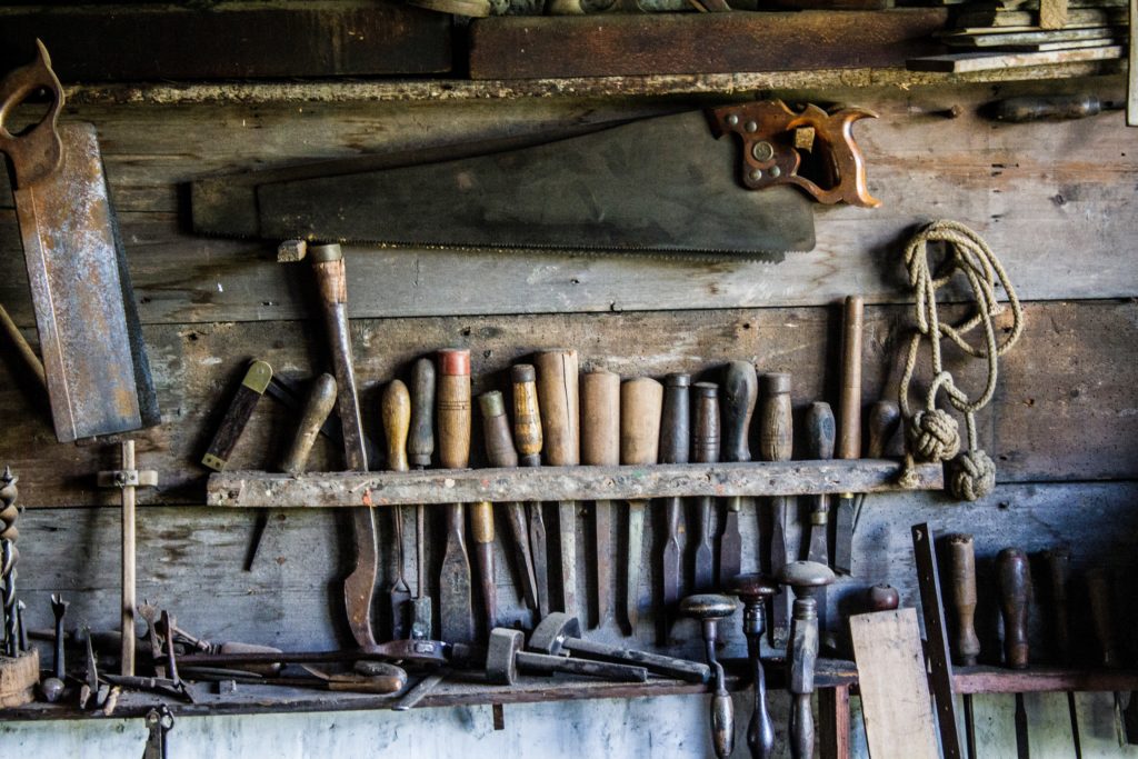 Overhead shot of old tools organized across the top of a workshop's workbench.
