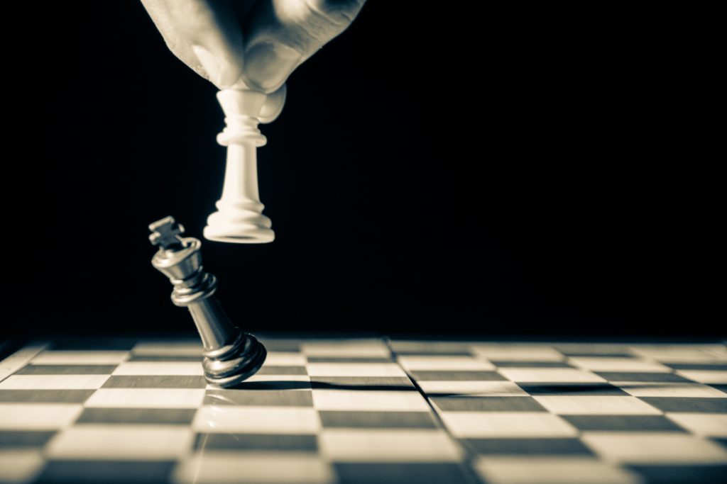 One chess piece knocking over an opponent's piece, signifying a victory.