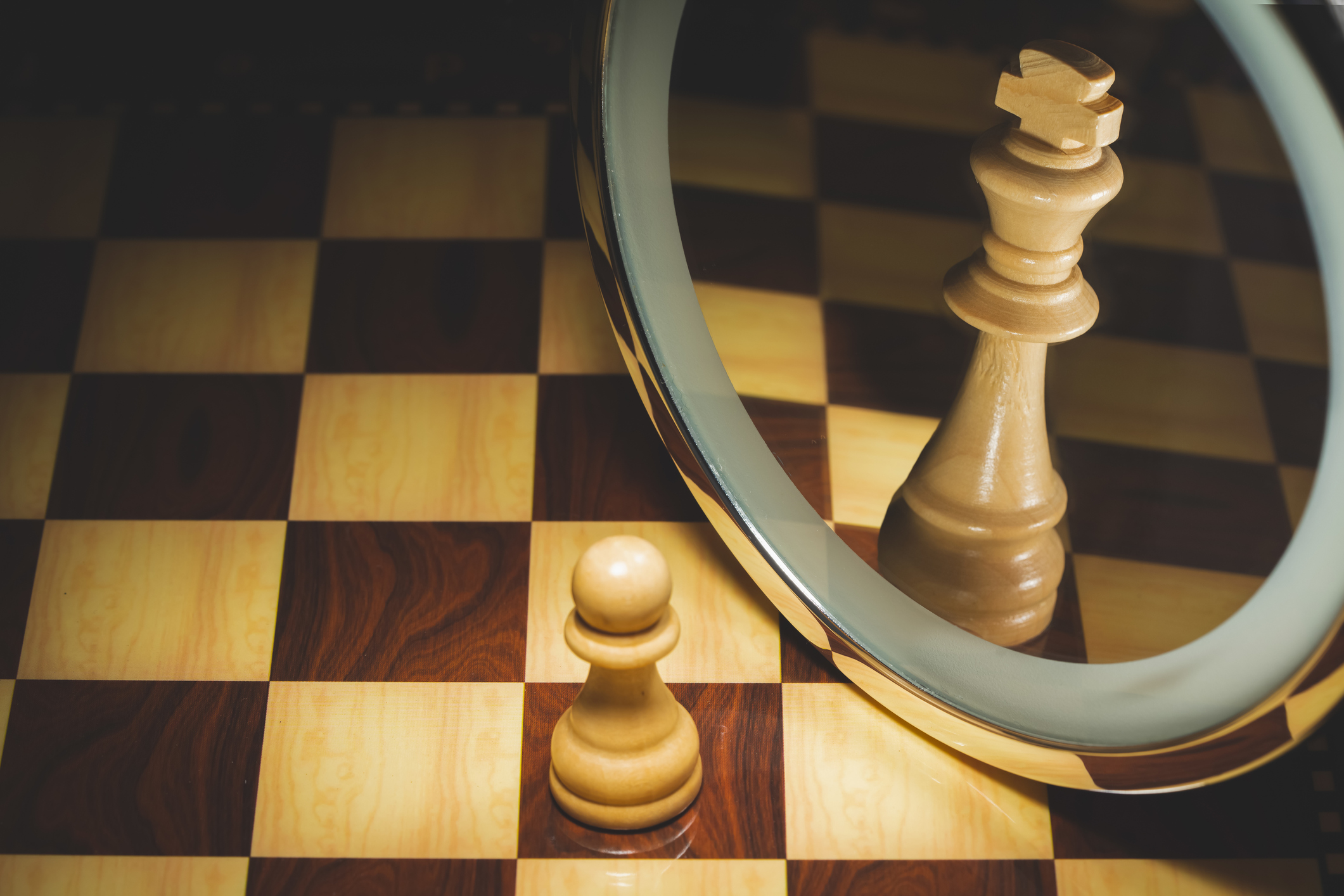 A chess pawn who sees himself as king in a mirror.