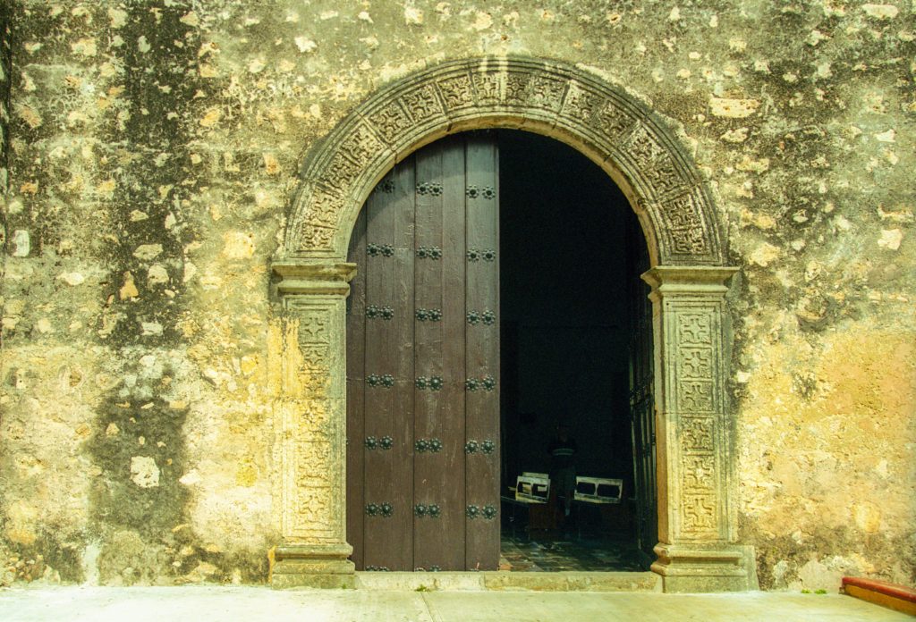 Arched entry door at a large wall; one side open, the other side closed.