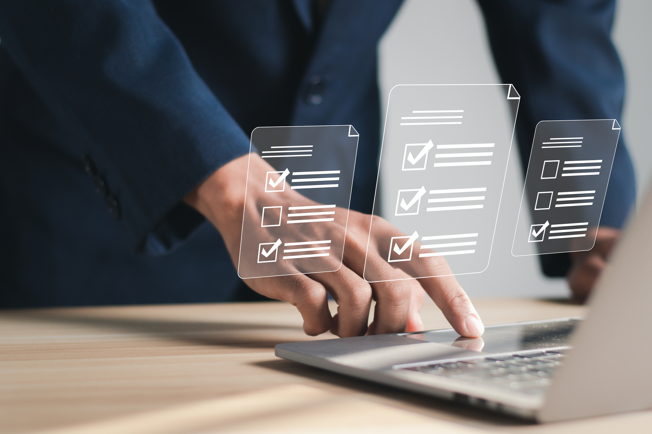 Businessman working at laptop computer and digital documents with questionnaire with checkboxes.