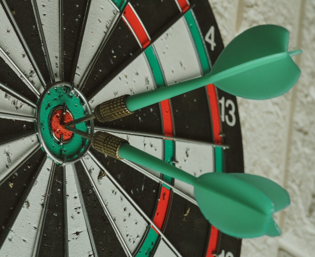 Dart board with three darts in the bullseye. 