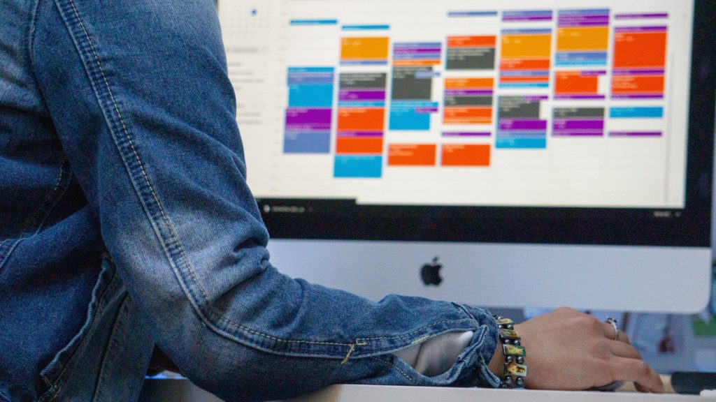 Man sitting at a computer with a weekly calendar being displayed on the screen.