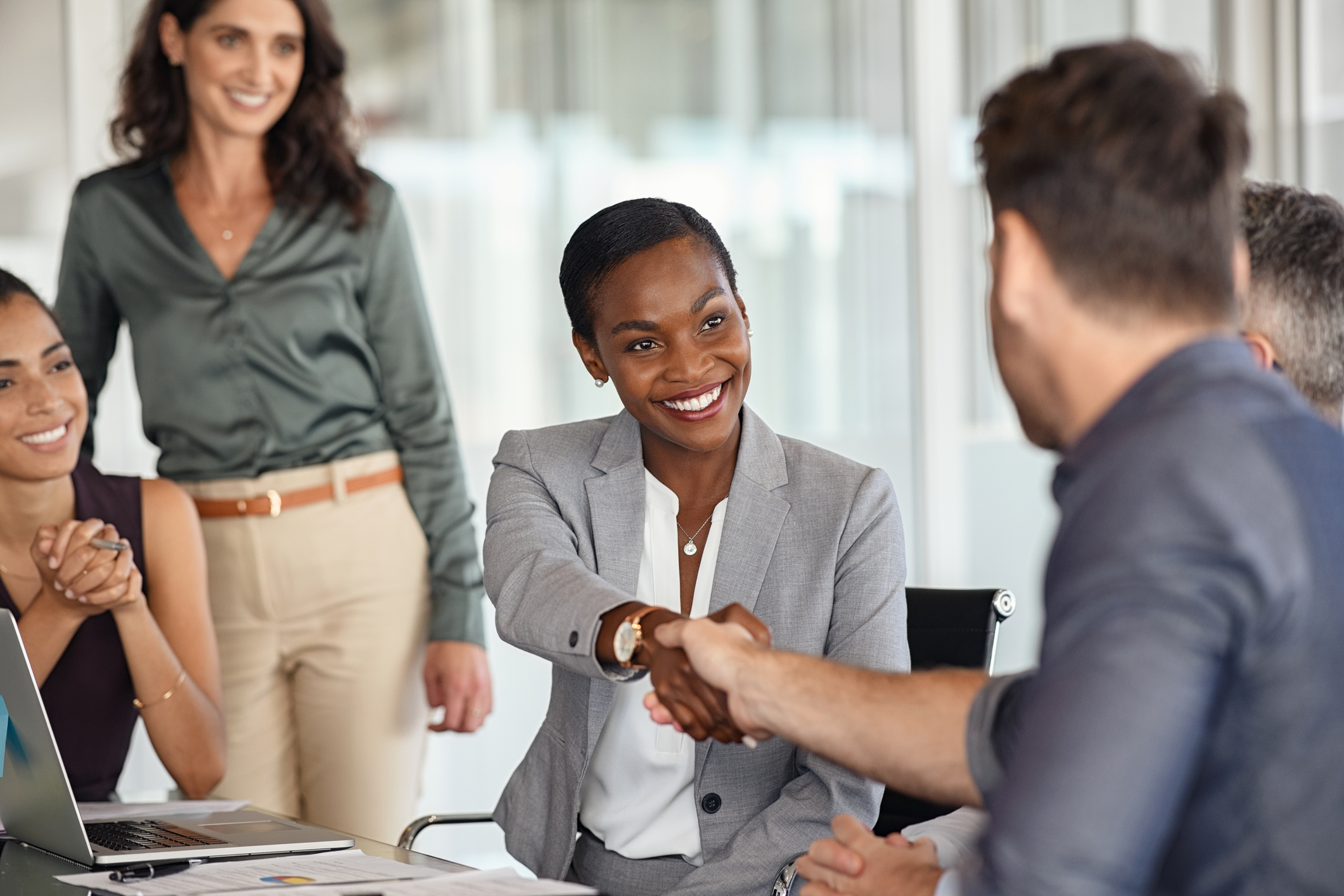 Two business people shake hands across a table.