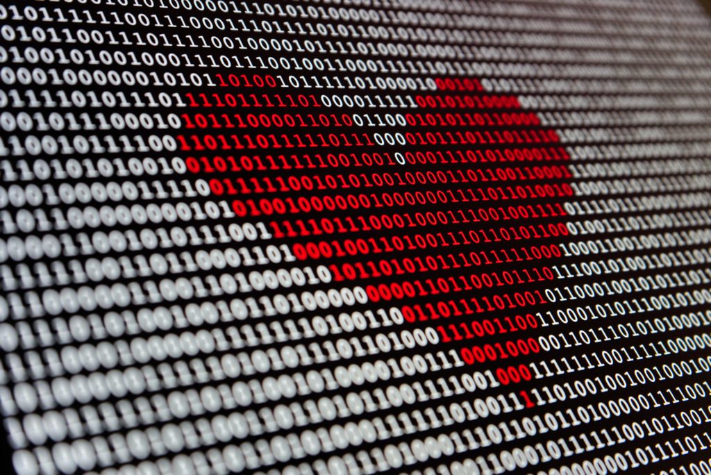Computer screen of data ones and zeros, with a red heart overlay.