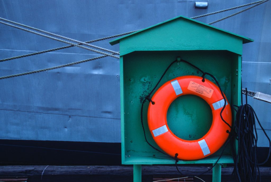 Image of an organize life preserver ring on the edge of a pier. 