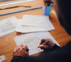 Image looking over the shoulder at a person drawing out a process flow on paper.