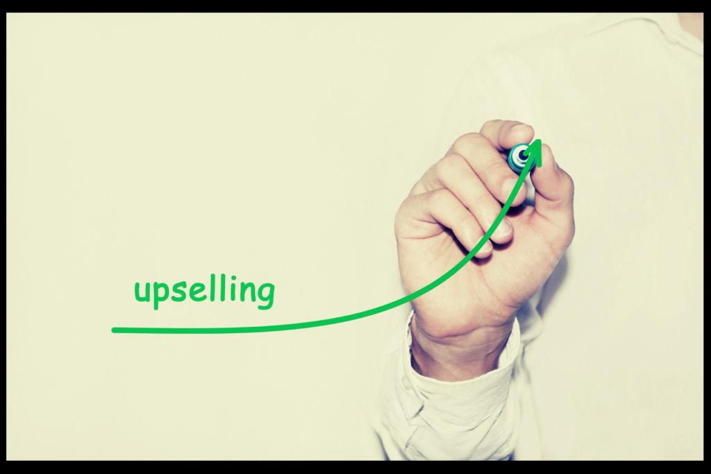Image of a green marker on a whiteboard, drawing an upward arc with the label, "upselling."