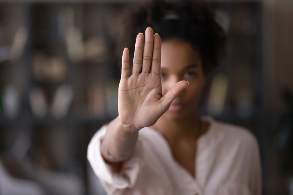 Woman holding up her hand, open palm facing outward, signaling "stop."
