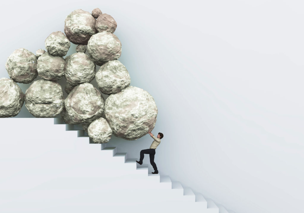Image of a man pushing back against a pile of boulders set to fall down a staircase. 