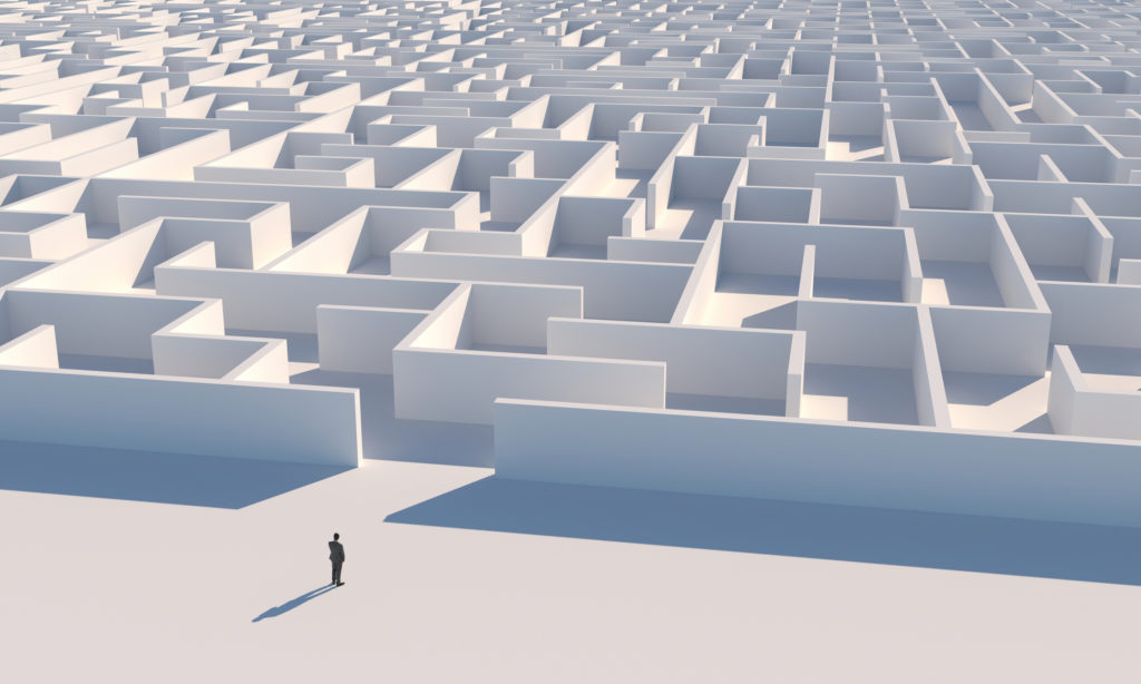 A man stands at the beginning of a dauntingly big and complex maze.