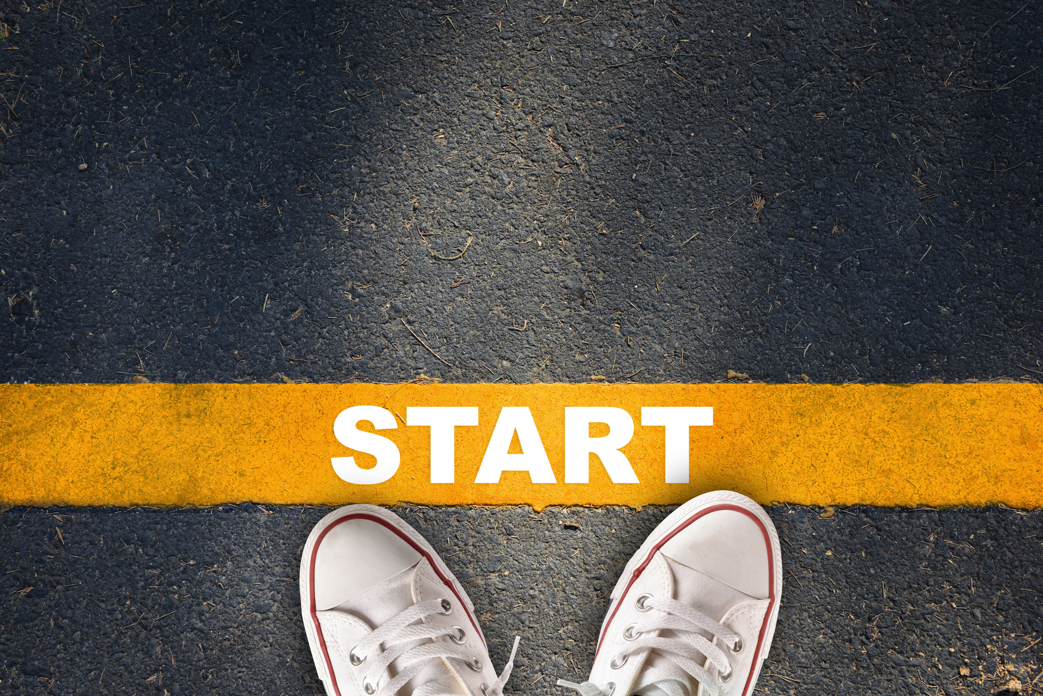 Downward view of a pair of shoes toeing a starting line.