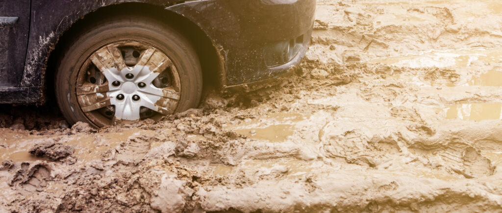 Image of a car's rear tires stuck in mud. 