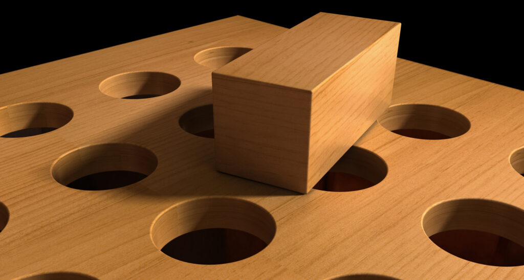 Image of a square peg lying atop of board of round holes.