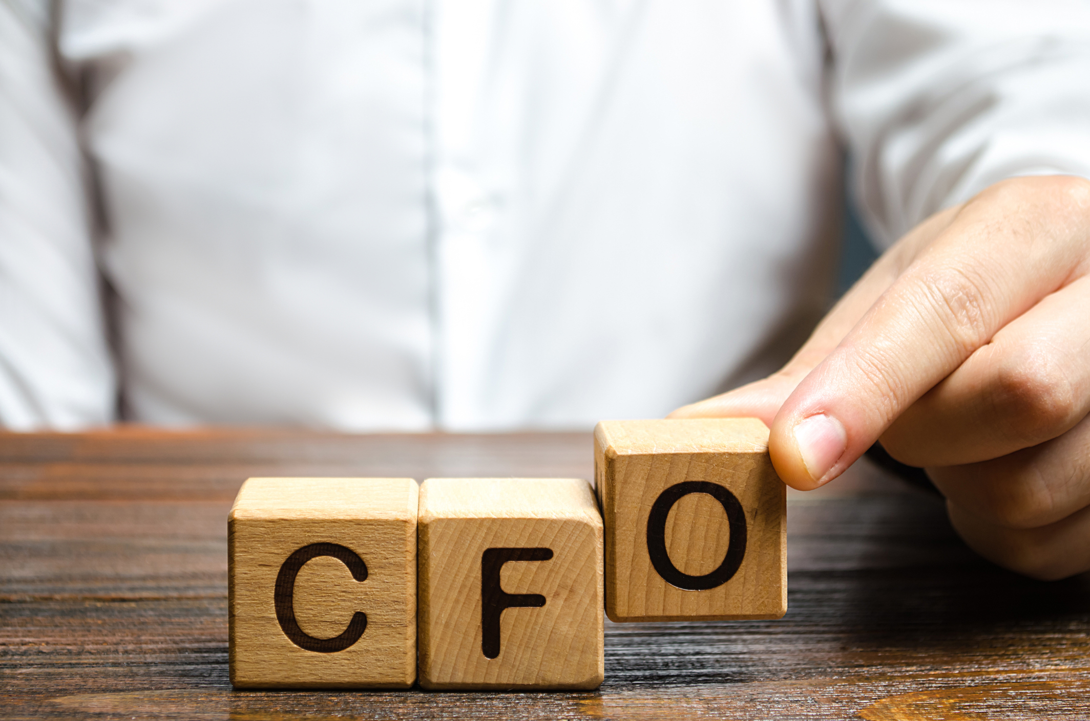 A man makes the word acronym abbreviation CFO with letter blocks.