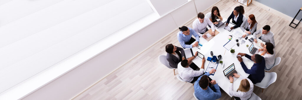 Group of business people around a round conference table discussing a purchasing process. 