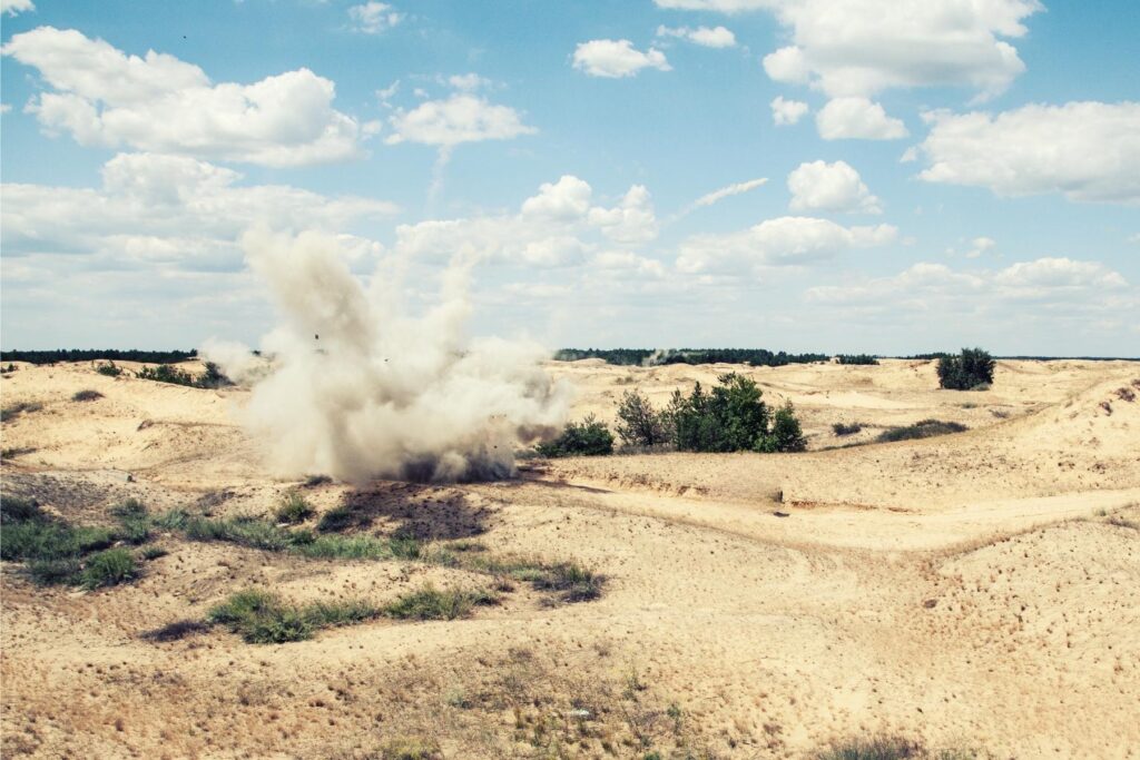 Image of a puff of dirt after an explosion in the desert.