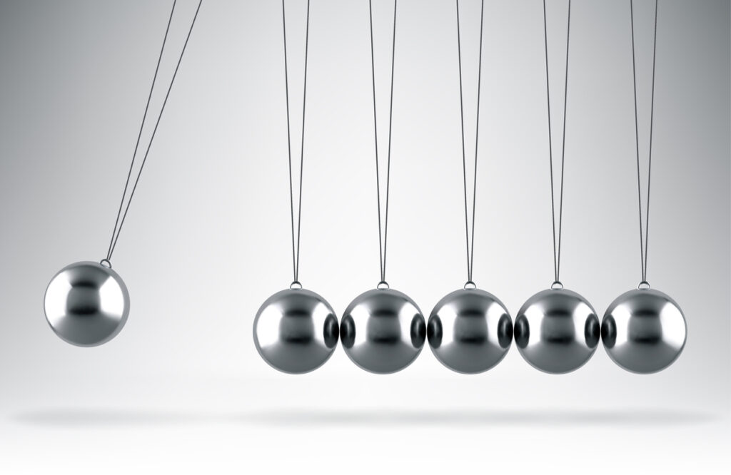 Image of a Newton Cradle, with the left most ball in motion.