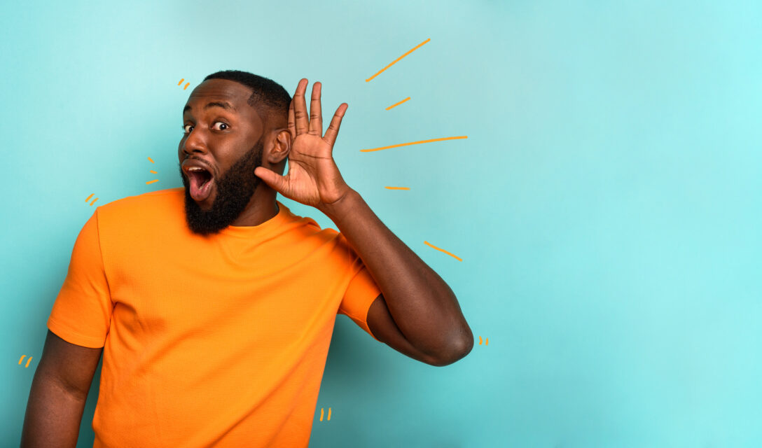 Man places his hand next to his ear to signal he hears you.