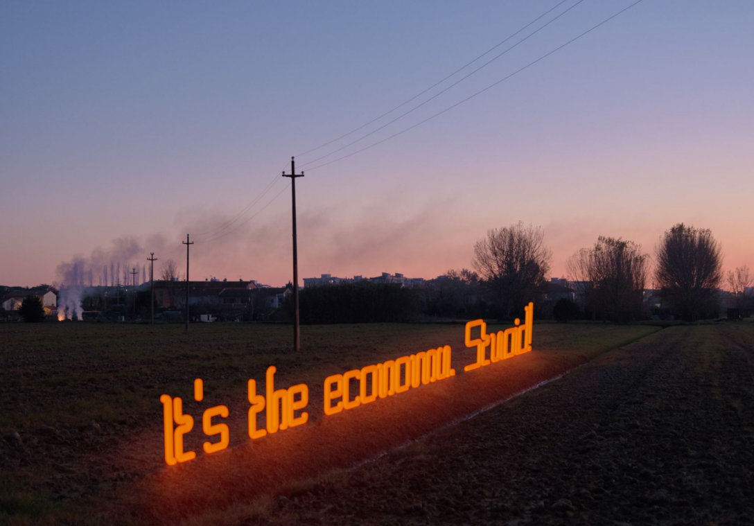 Neon sign reading, "It's the economy, Stupid."