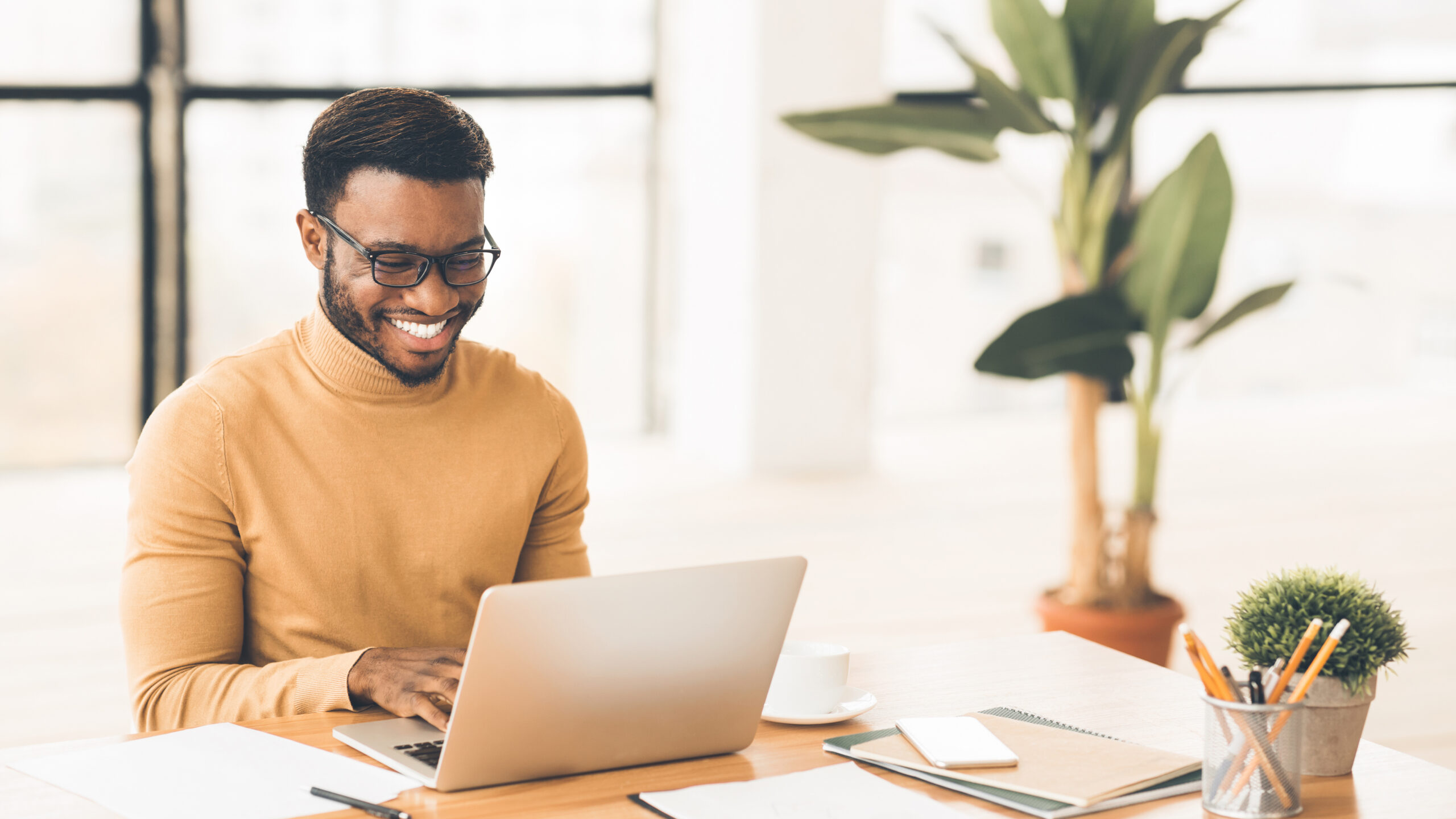An African American male working professional sitting at a desk working on a laptop