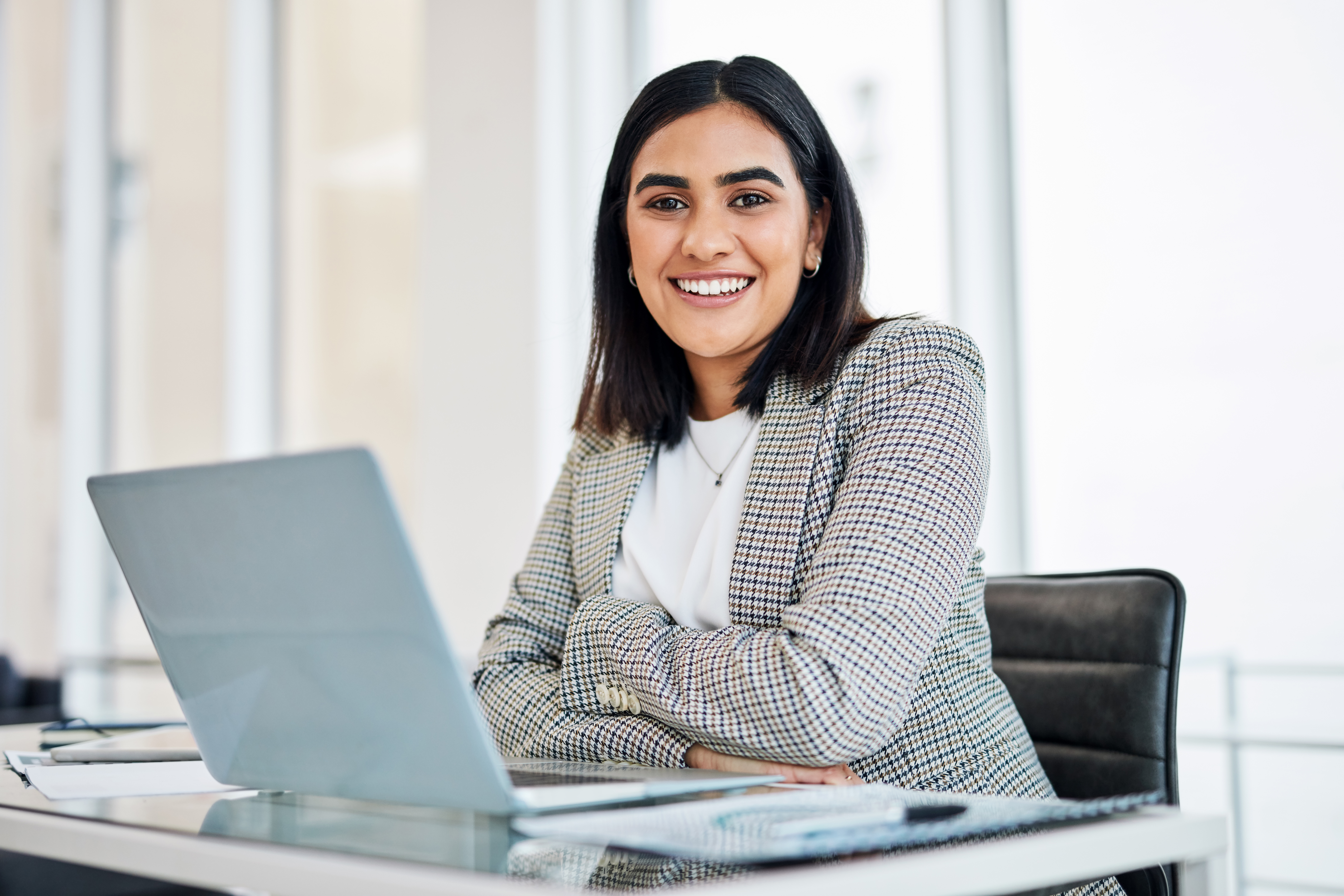 A female working professional sitting at a desk working on a laptop