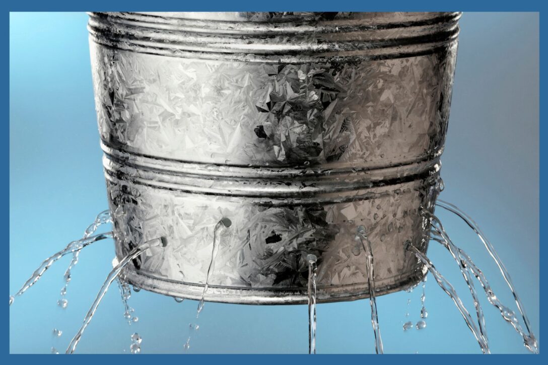 silver bucket with holes in the sides leaking water