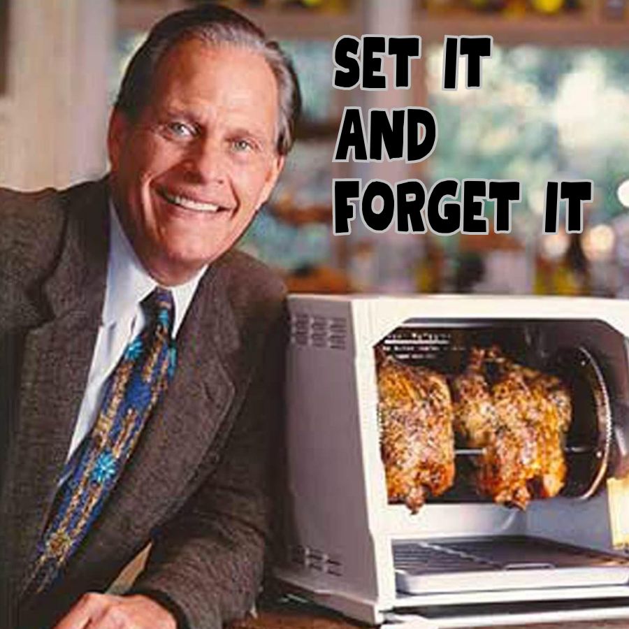 Man standing next to a toaster oven with roasting chickens inside