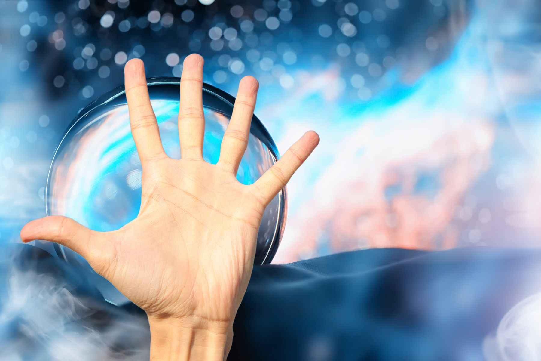 human hand holding up five fingers with a crystal ball in the background