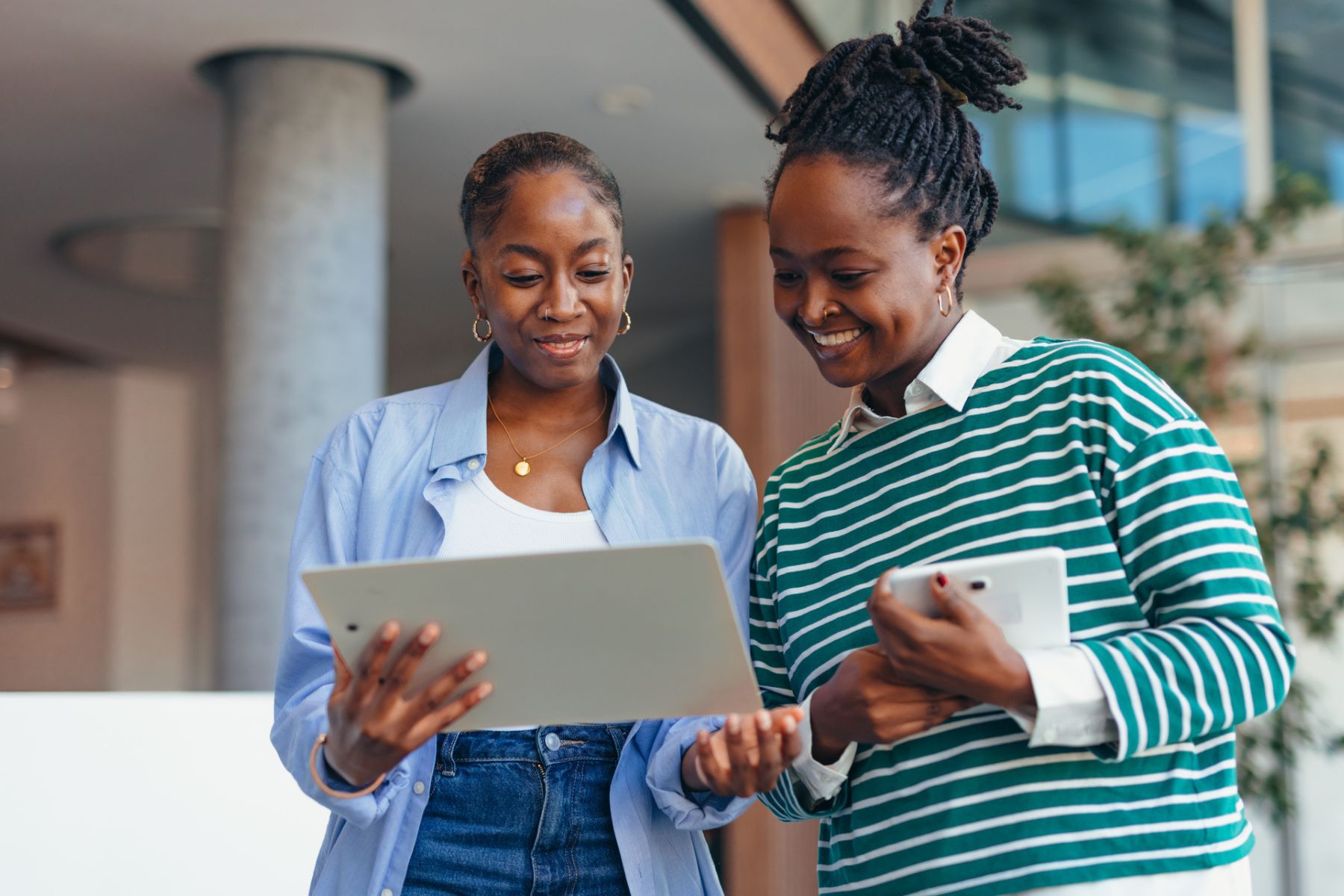 two women in an office environment looking at a tablet together